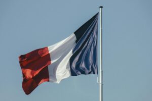 The French national flag waving against a bright blue sky, symbolizing liberty and national pride.